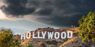 Hollywood sign on hills under cloudy sky.