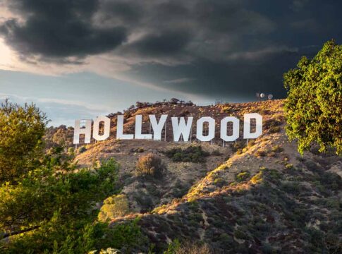 Hollywood sign on hills under cloudy sky.