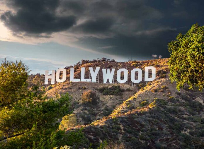 Hollywood sign on hills under cloudy sky.