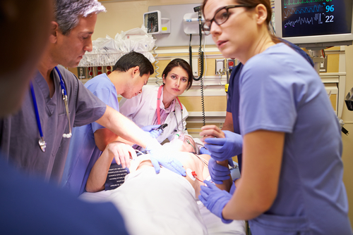 Medical team working on patient in hospital emergency room.