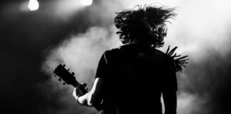 Silhouette of guitarist performing on stage with hair flying.