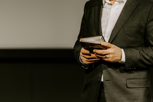 Person in suit holding a Bible.