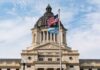 South Dakota Capitol building with American and state flags.