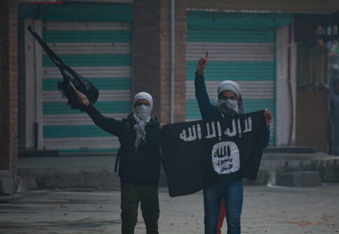 Two masked individuals holding a flag and gun.