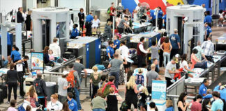 Crowd at an airport security checkpoint with TSA officers.