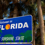 Welcome to Florida sign with palm trees background.