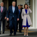 Group of officials walk outside a building entrance.