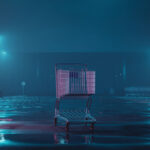 Store PURGE Escalates—Another 645 Stores GONE In 2026… A shopping cart in an empty parking lot illuminated by neon lights in a foggy night