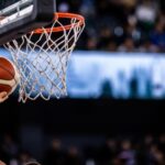 A basketball player reaching for the hoop with a ball