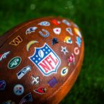 Close-up of an NFL football featuring various team logos on its surface