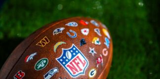 Close-up of an NFL football featuring various team logos on its surface