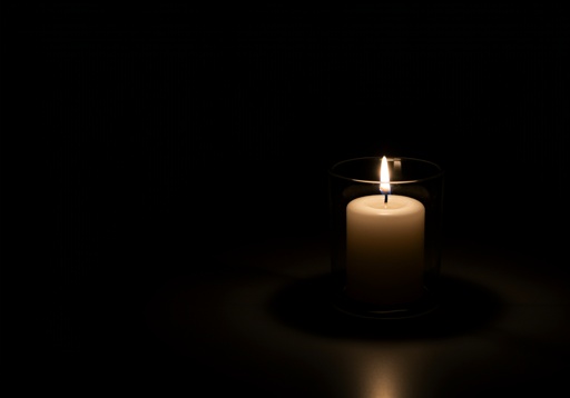 A lit candle in a glass holder against a dark background
