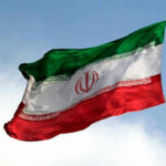 Tucker RIPS Trump Over Forbidden War Move… Iranian flag flying against a clear sky.