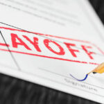 Layoff notice being signed with a pen.