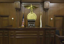 Supreme Court BLOCKS NFL’s Private Game Plan… Judges bench in an empty courtroom, scales emblem above.