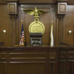 SHOCKING Indictment Looms: Justice at Last? Judges bench in an empty courtroom, scales emblem above.