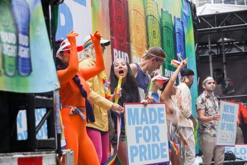 People celebrating at Pride parade, holding signs and flags.