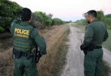 Special Interest Aliens BUSTED at Border! Two U.S. Border Patrol officers standing on a dirt path.