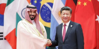 Saudi Crown Prince and Xi Jinping shaking hands, flags behind.