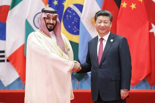 Saudi Crown Prince and Xi Jinping shaking hands, flags behind.