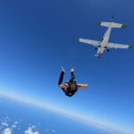Skydiver jumping from airplane in clear blue sky
