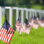American flags beside gravestones in a cemetery.