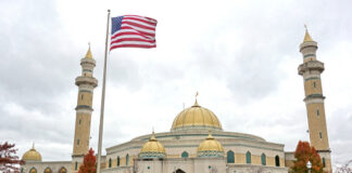 A mosque with a golden dome and minarets, featuring an American flag in front