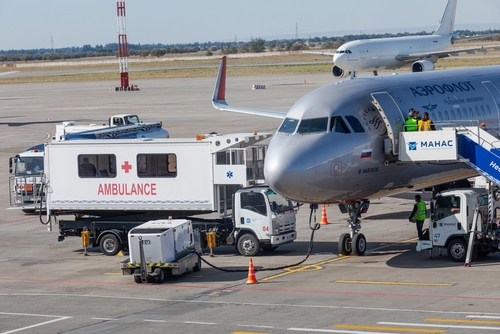 shutterstock_2387383303.jpg An airplane at an airport with an ambulance and ground crew nearby