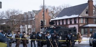 Police officers at a crime scene with a tactical vehicle in a snowy urban area