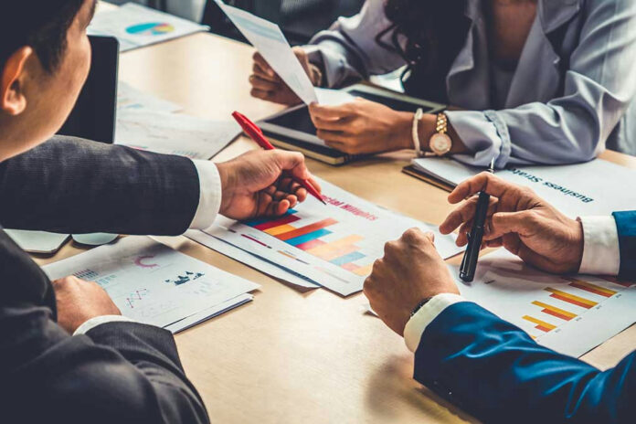People discussing charts and graphs at a meeting.