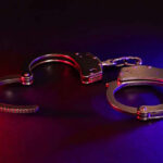 Handcuffs illuminated by red and blue lights.