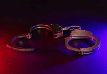 Dying Teen Handcuffed – Cops Bought the Lie Handcuffs illuminated by red and blue lights.