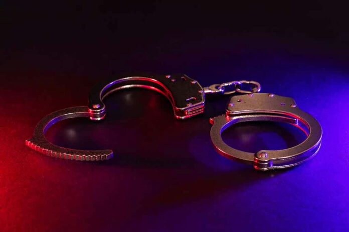 2423548283 Handcuffs illuminated by red and blue lights.