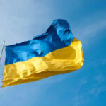 Ukrainian flag waving against blue sky.