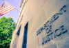 Faith Clash Explodes — DOJ Enters Department of Justice building with American flag.