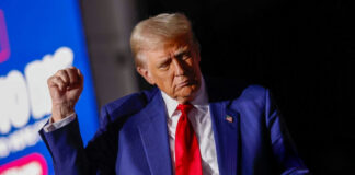 Man in blue suit with red tie speaking
