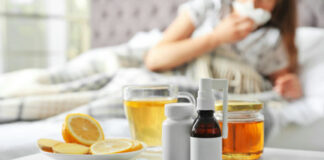 Medicines, honey, and lemon on table beside sick person.