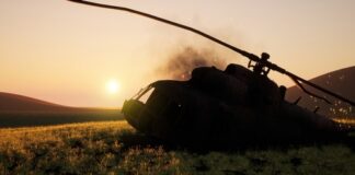 Abandoned military helicopter in a grassy field during sunset