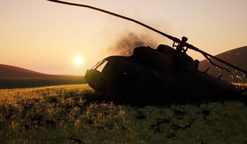 Abandoned military helicopter in a grassy field during sunset