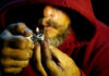 Tobacco Giant’s ‘Efficiency’ Bloodbath Person igniting a pipe, wearing a red hoodie.
