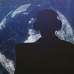 Silhouette of person with headphones in front of globe.