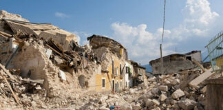 Rubble from collapsed buildings in earthquake-hit area. Clear sky.