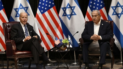 Two political leaders seated with flags in the background