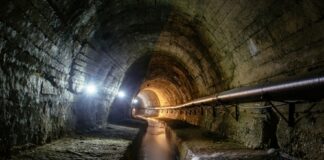 An underground tunnel with flowing water and dim lighting