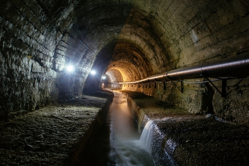 An underground tunnel with flowing water and dim lighting