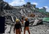 Rescue workers survey collapsed building debris