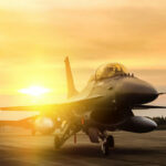 Fighter jet taxiing during sunset on an airstrip.