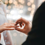 Groom placing ring on brides finger at wedding.