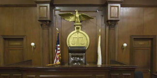 Judges bench in an empty courtroom, scales emblem above.