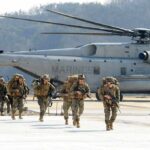 Retaliation Or Prelude? Washington’s Risky Bet Soldiers disembark and walk past a large military helicopter